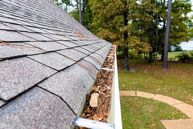 power washing technician clearing debris from gutters